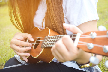 Fototapeta premium Young woman playing on Ukulele