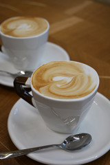 Delicious foamy cappuccino on a white cup on a plate