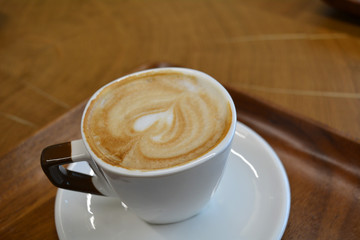 Delicious foamy cappuccino on a white cup on a plate