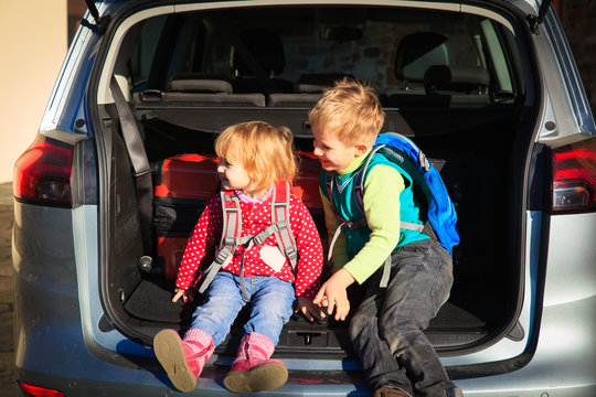 family travel - little boy and toddler girl with luggage in the car