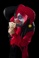 Fieser Clown hält Spielkarten in der Hand, schwarzer Hintergrun