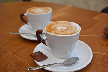 Delicious foamy cappuccino on a white cup on a plate