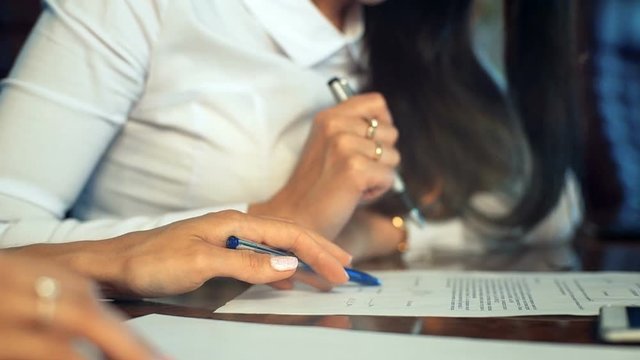Close-up of female hands making notes in the notepad at office during interview.