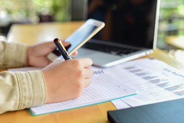 Woman typing text message on smart phone in a cafe. Cropped imag