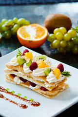Beautiful fresh dessert millefeuille with pineapple and kiwi served with fruit sauce