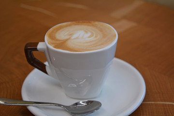 Delicious foamy cappuccino on a white cup on a plate   