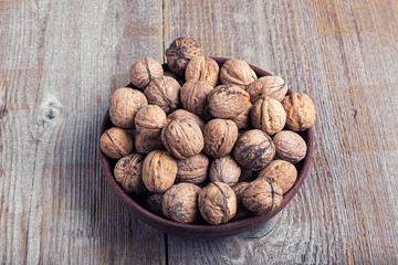 walnuts in a clay plate on a wooden background. top view