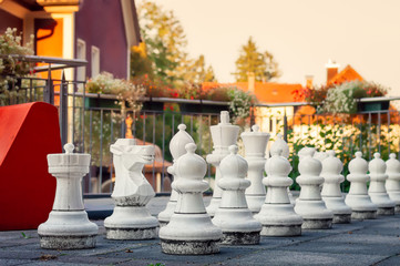 Giant White Plastic Chess Pieces on a Terrace at Sunset