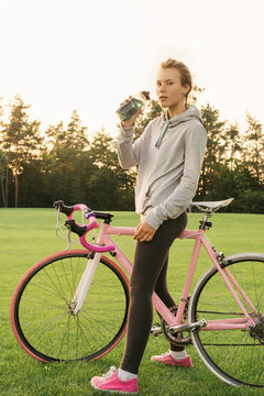 Tired woman quenches thirst after riding a bike