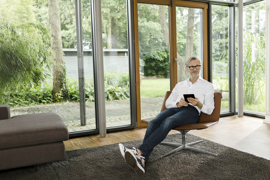 Man sitting with tablet on chair in his living room