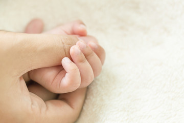 Baby hand holding finger mom on vintage tone. (Selected focus)