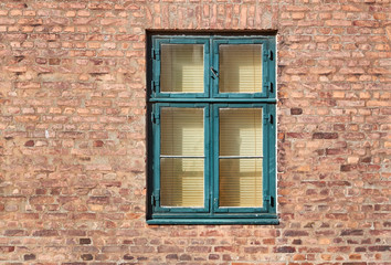 Green painted typical danish, or scandinavian style window, fastened in a red brick building facade