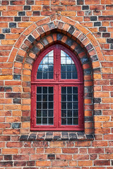 Fototapeta na wymiar Pointed arch shaped antique window with a mounted metal grid fastened in the facade of the former monastery Karmeliter in Elsinore Denmark