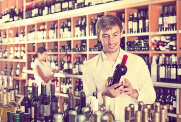 Cheerful man buying bottle of wine