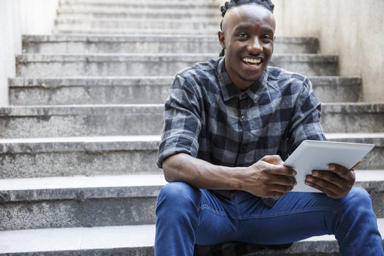Young man sitting on stairs, using digital tablet