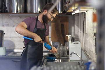 Man cleaning glass bottle with a brush