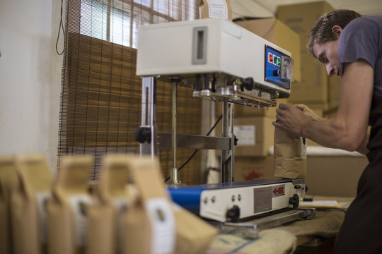 Man working at coffee bean packaging vacuum sealer