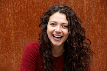 Attractive young woman laughing against brown wall