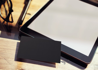 Closeup Modern Tablet Blank Screen,Glasses Wood Table Inside Interior Coworking Studio Place.Empty Mockup Design Black Business Card Corporate Message Background.Mock Up Private Objects Text.Blurred.