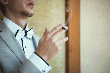 elegant young fashion man in a suit smoking cigar