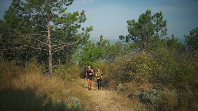 Young sportive couple smiling jogging up on hill firth background Slow motion