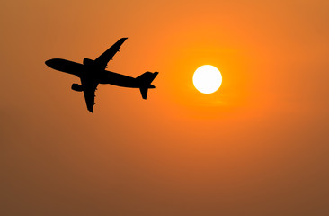 Silhouette of big airplane on beautiful orange sunset background, fast aerial transport, traveling and voyage concept