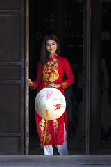 Beautiful woman with Vietnam culture traditional dress, Ao dai is famous traditional costume , vintage style, Hoi an Vietnam, holding hat