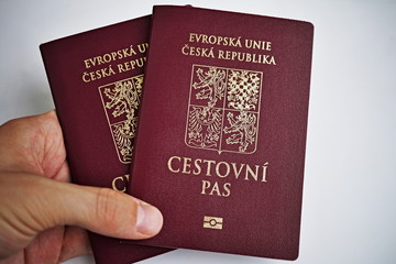 Male hand holding red Czech passport with a state symbols (lions and eagles) and captions Czech Republic and European Union in Czech language