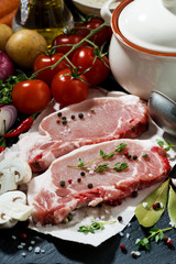 two pieces of raw pork and fresh ingredients for soup, closeup