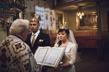 Bride and groom stand in crowns during the engagement ceremony