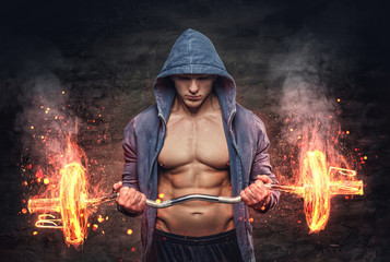 Male in a blue hoodie holds the burning barbell.