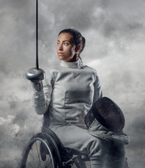 Female fencer in wheelchair with safety mask of a face holding r