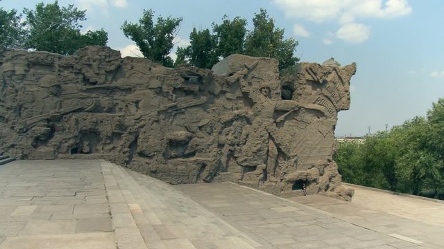 Wall Sculpture Made of Concrete Stone With Military Scenes on It. Armed Soldiers With Rifles Fighting.wide Concrete Stairs. Blue Sky. Green Tree