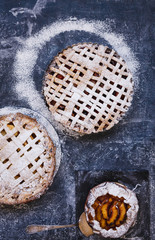 Fruit pie crust and fruit galette over blue flourish table.