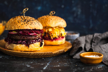 Delicious purple cabbage burger with beef cutlet served on a rustic round wooden counter. 