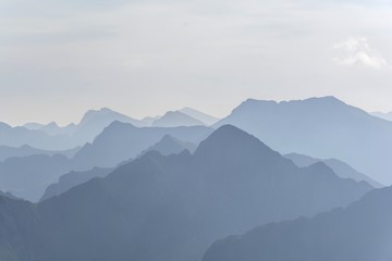 Silhouette of blue mountains in the fog. View of Moldoveanu peak, the highest peak from Romanian Carpathian Mountains range. Seamless background.