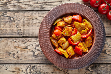 Chicken jalfrezi Indian spicy curry chilli meat and vegetables healthy dietetic asian food in clay dish on vintage table background.