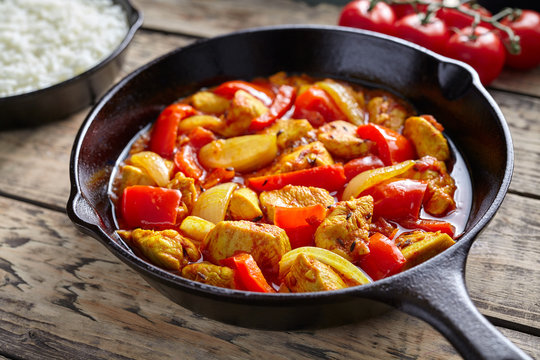 Chicken jalfrezi healthy traditional Indian culture restaurant meal curry spicy fried meat with chilli and vegetables, tomatoes, pepper, onion, asian food in cast iron pan on vintage table background