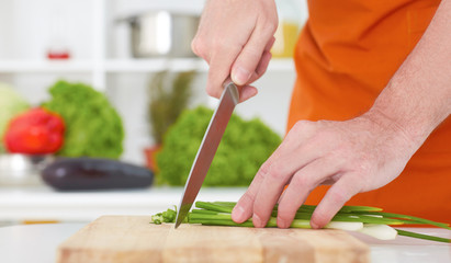 Cropped image of a chef cook cutting green onion on the cutting board. Healthy eating, dieting, slimming and weigh loss concept.