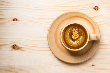 Top view of latte art coffee cup with coffee bean on pine wood table