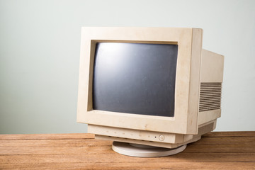 old and obsolete computer monitor on old wood table with concrete wall background