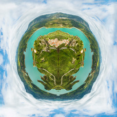 Fototapeta premium Little planet composition of an aerial view of the top of a green earth with trees and seas, in a cloudy blue sky. Concept of green ecosystem conservation.