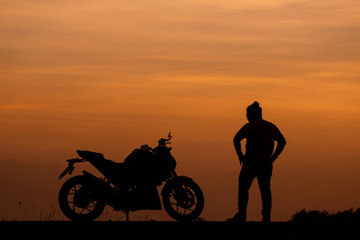 Fototapeta na wymiar Silhouette man and his motorcycle To live a lifestyle. with beautiful the sky at sunset..Background,