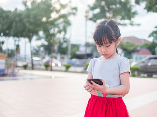 Asian child girl play smart phone, in the garden