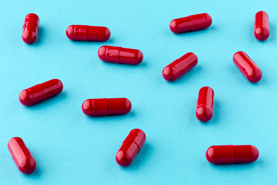 Drug red capsules scattered on the blue background