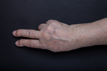 Hands of elderly woman on black background