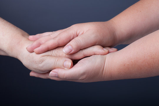 Hands of elderly and young women on black background