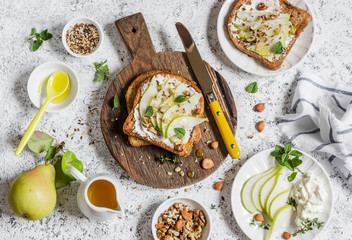 Toast with cheese, pear, honey and nuts. Delicious breakfast or snack on a light background, top view.