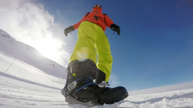 Snowboarders nightmare – going to a stand still on a snow trail, low angle front view
