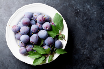 Garden plums in plate on stone table